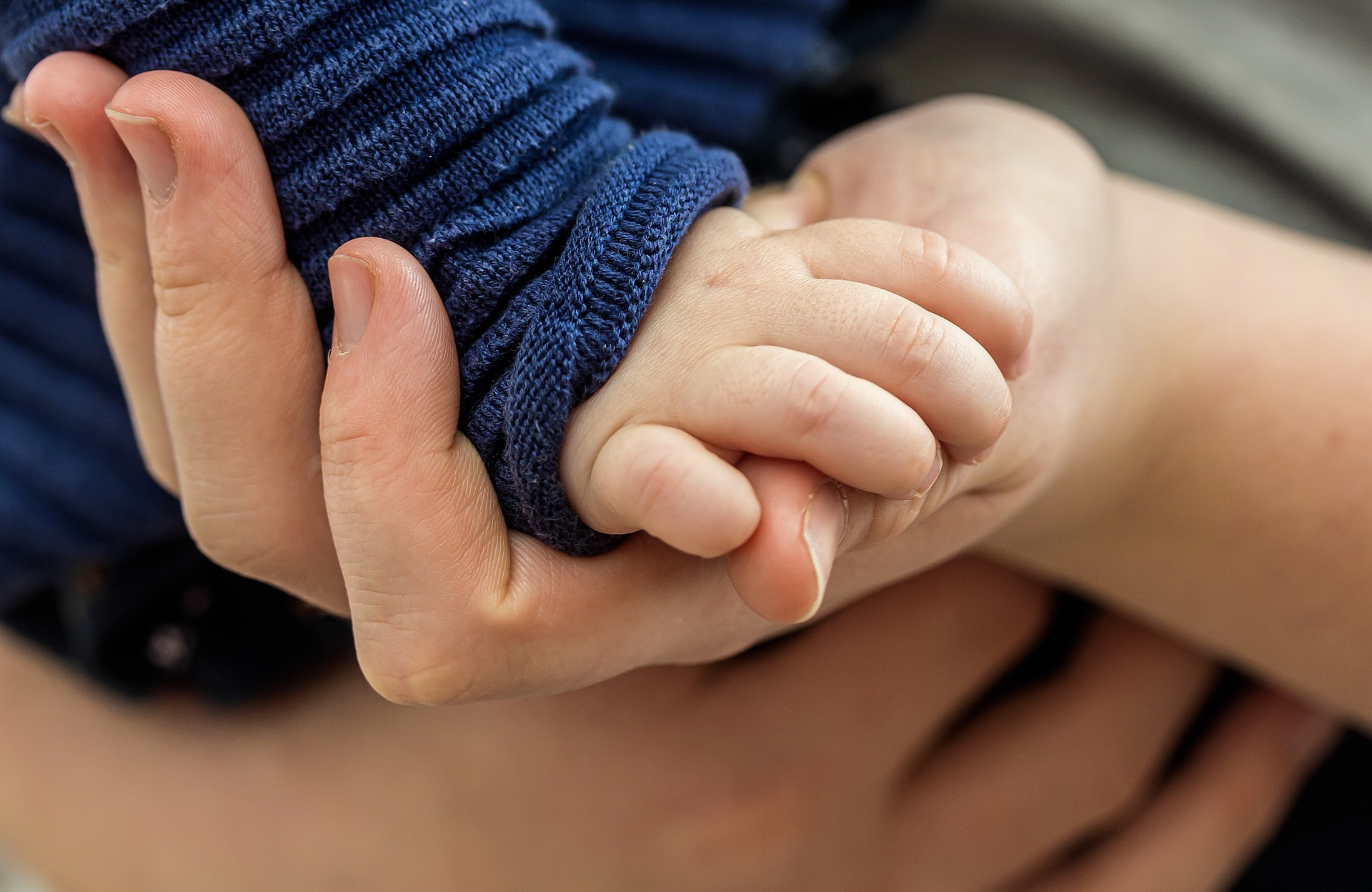 Erwachsene Hand hält die eines Babys